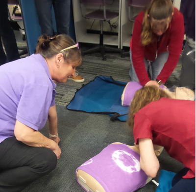 Owner & Trainer Zoe of B-Ready First Aid assisting a student with breathing technique on an adult manikin for a corporate customer.
