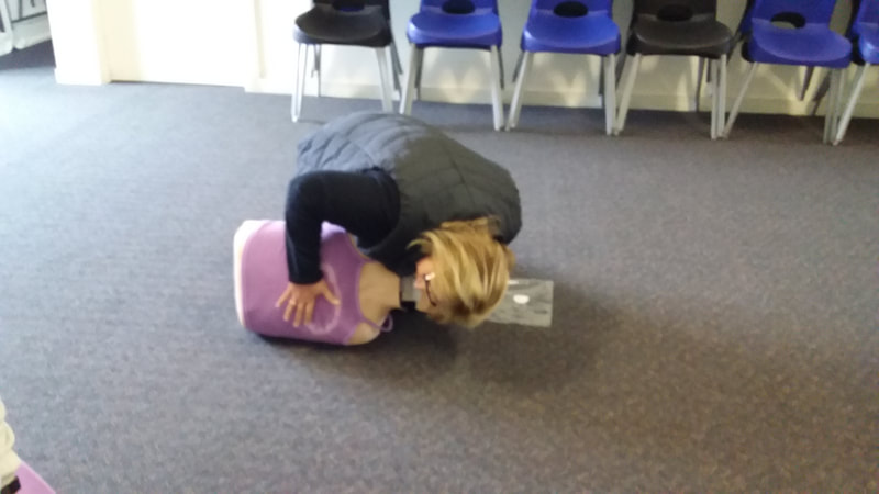 A student of B-Ready First Aid demonstrating how to assess breathing in an adult manikin. 